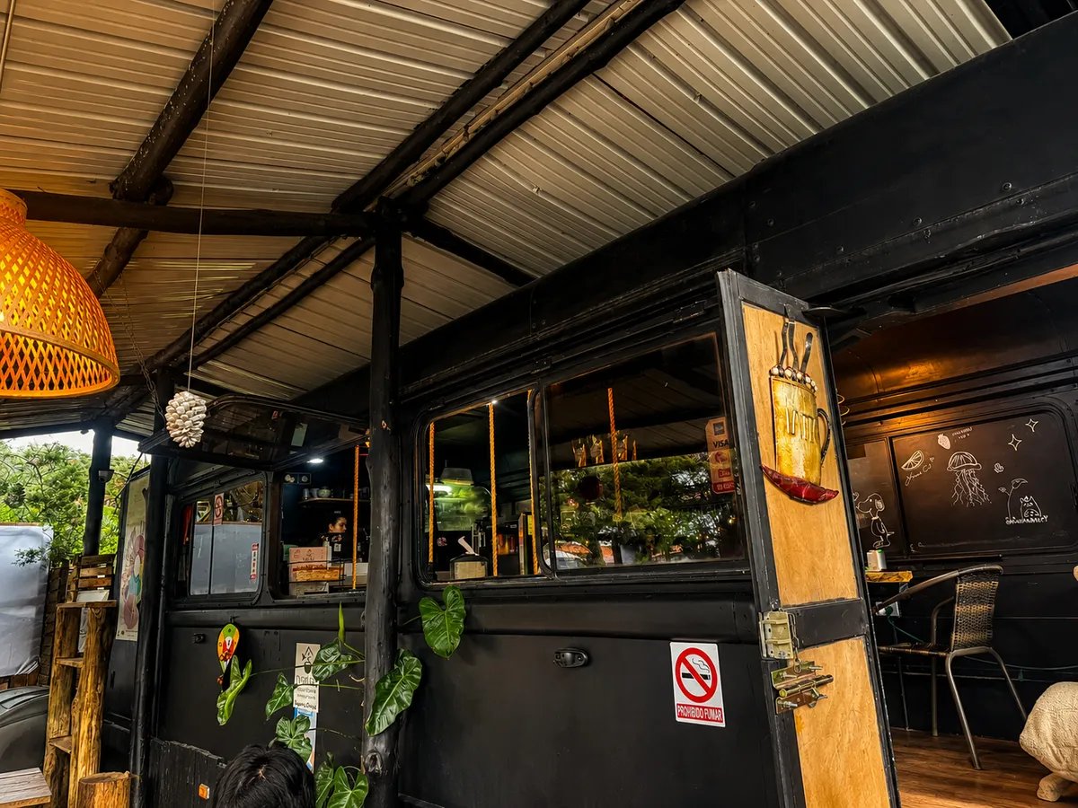 El bus negro convertido en barra de café, con lámparas de mimbre